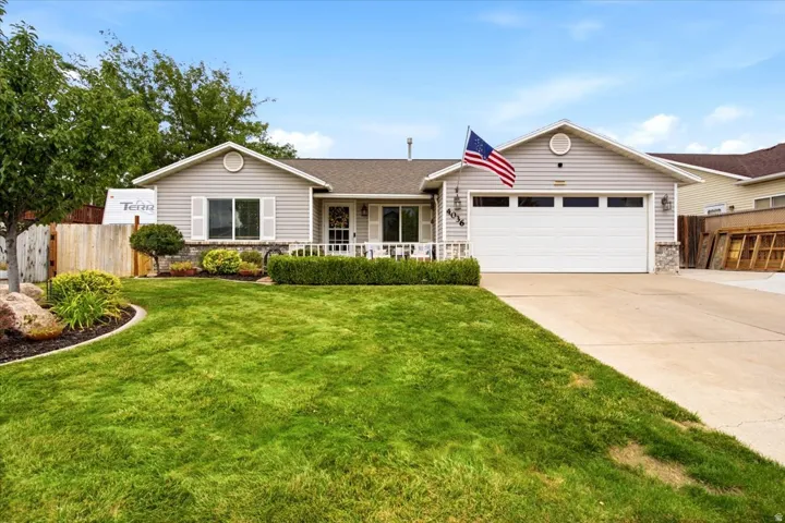 Siding exterior with stone accents, attached garage, concrete driveway, and front porch with railing