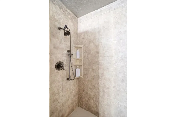 Tiled shower enclosure featuring a dual shower head system and built-in shelving