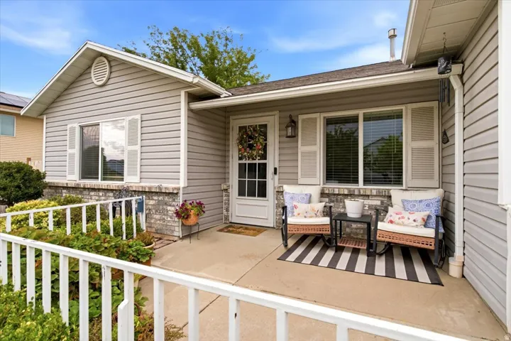 Inviting covered porch with a partial brick facade, shutters, and a front entry door with a decorative glass insert