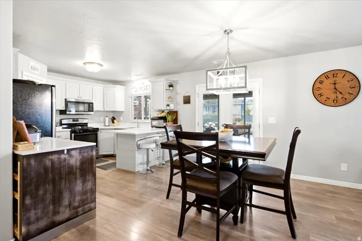 Kitchen and dining area featuring white cabinetry, light countertops, wood-finish flooring, and a dining light fixture