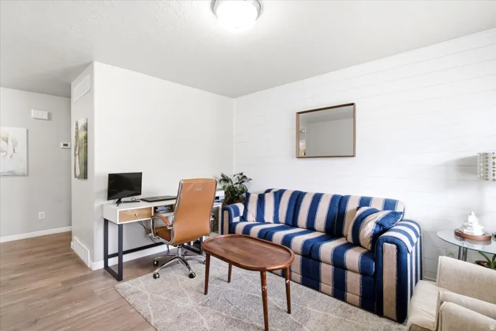 Wood-finish flooring, accent wall with horizontal paneling, and recessed ceiling lighting