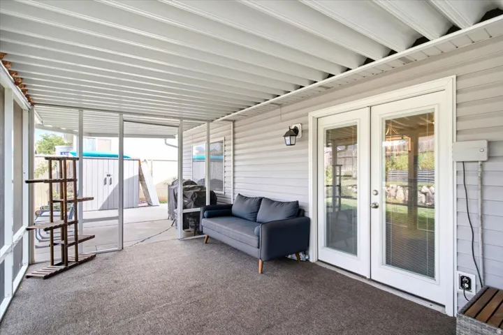 Screened patio with a covered ceiling, dual French doors, and exterior wall lantern
