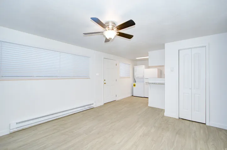 Open-concept living area featuring wood-finish flooring, a ceiling fan with integrated lighting, and a window with blinds