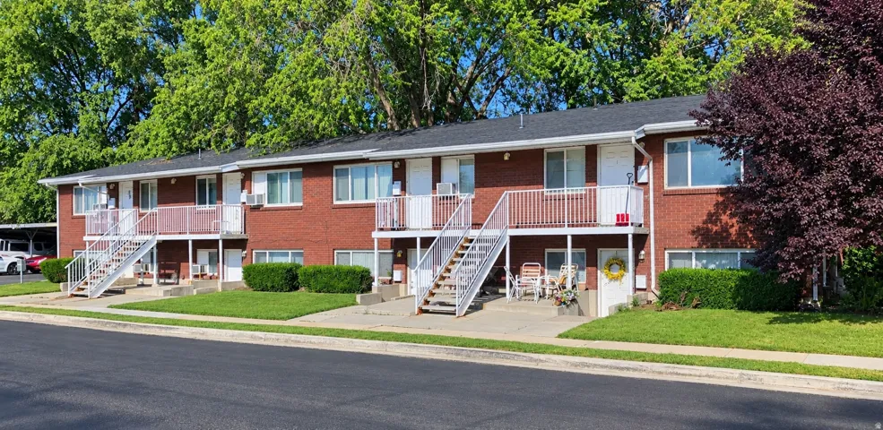 Brick exterior construction featuring white window frames, second-story balconies, and mature landscaping