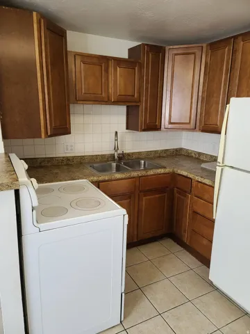 Kitchen featuring wood cabinetry, tiled backsplash, and stone-look countertops