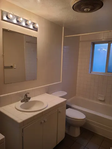 Tiled vanity with integrated sink, chrome faucet, and under-sink storage