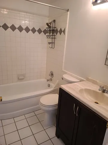 White tiled shower surround with decorative gray diamond-patterned accent tiles