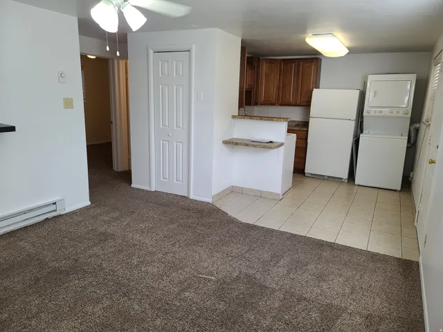 Kitchen area with wood-finish cabinetry, tile flooring, and a stone-finish breakfast bar