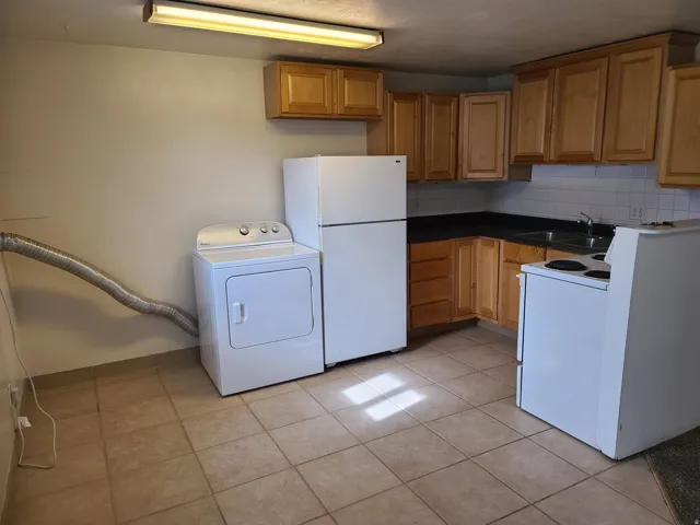 Kitchen featuring wood-finish cabinetry, dark countertops, and tile flooring
