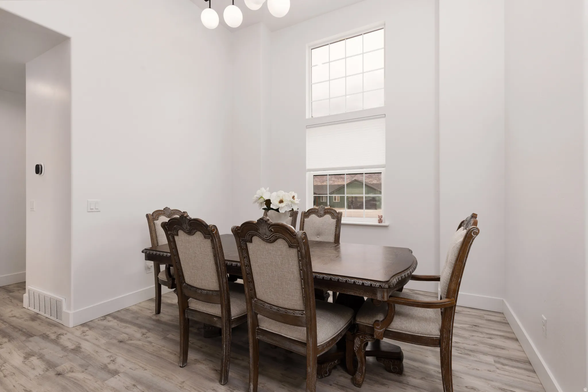 High ceilings with a contemporary multi-globe light fixture, wood-finish flooring, and a multi-pane upper window