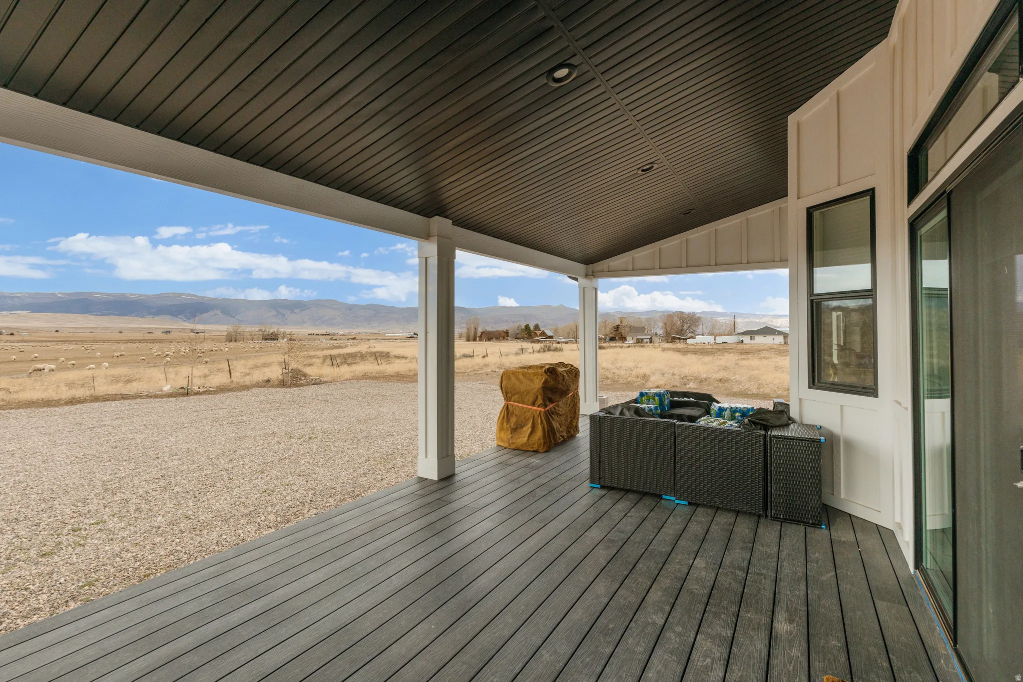 Expansive covered porch featuring composite decking, white support columns, and a sloped ceiling