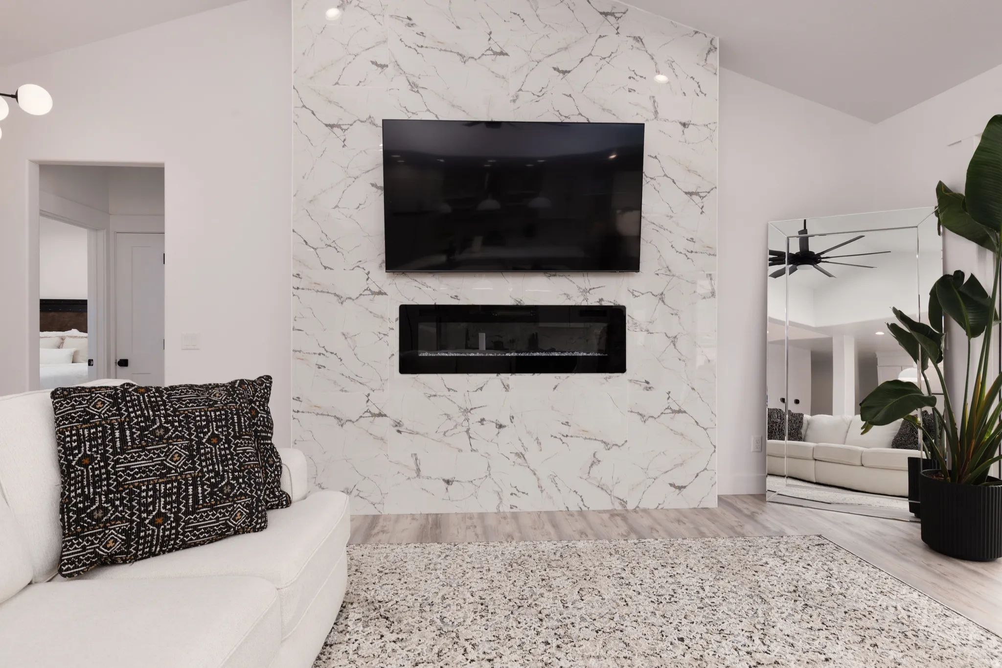 Vaulted ceiling, full-height decorative paneling, built-in linear fireplace, and wood-finish flooring