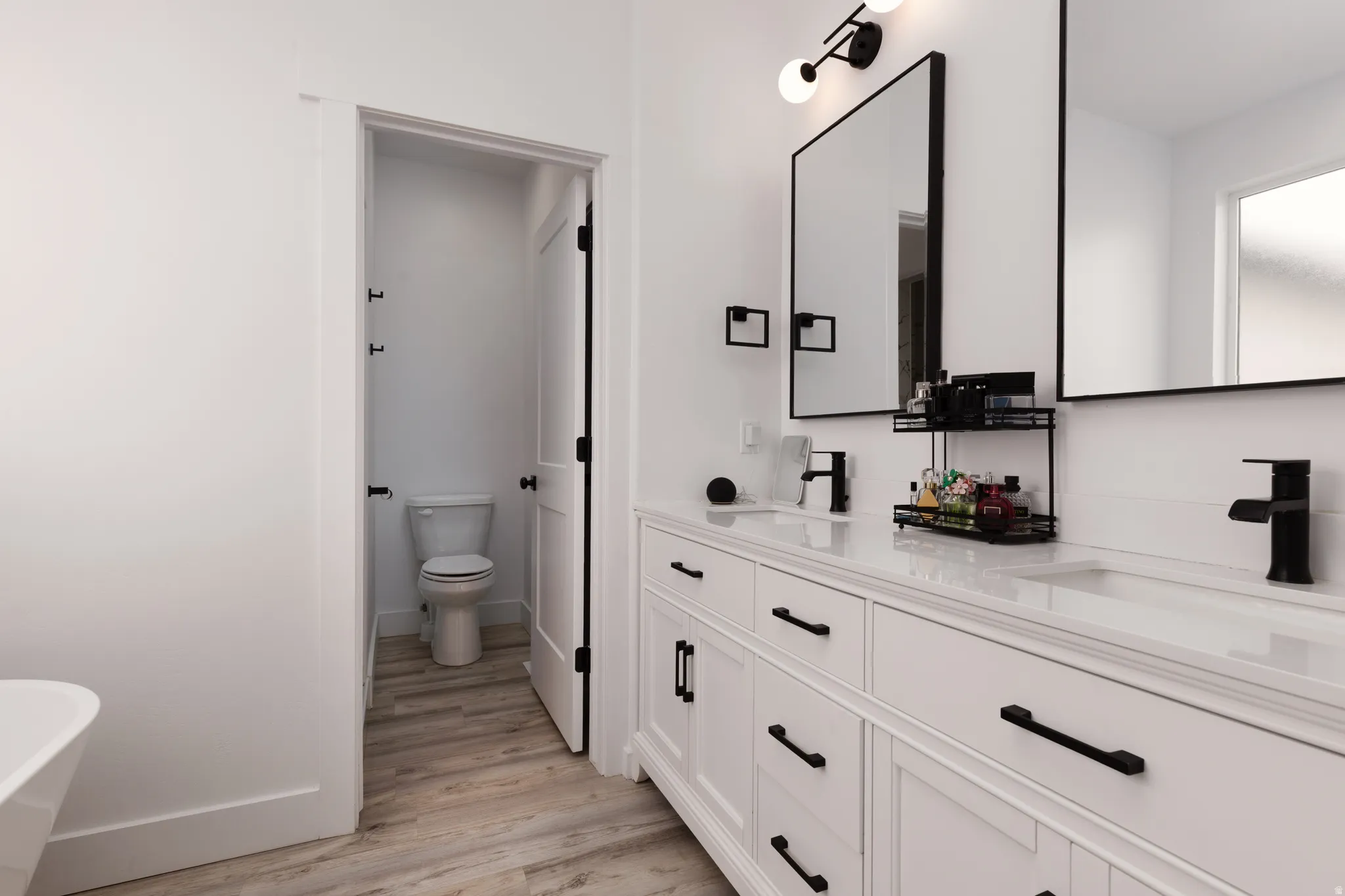 Dual vanity with undermount sinks, white cabinetry, quartz countertop, matte black fixtures, and framed mirrors