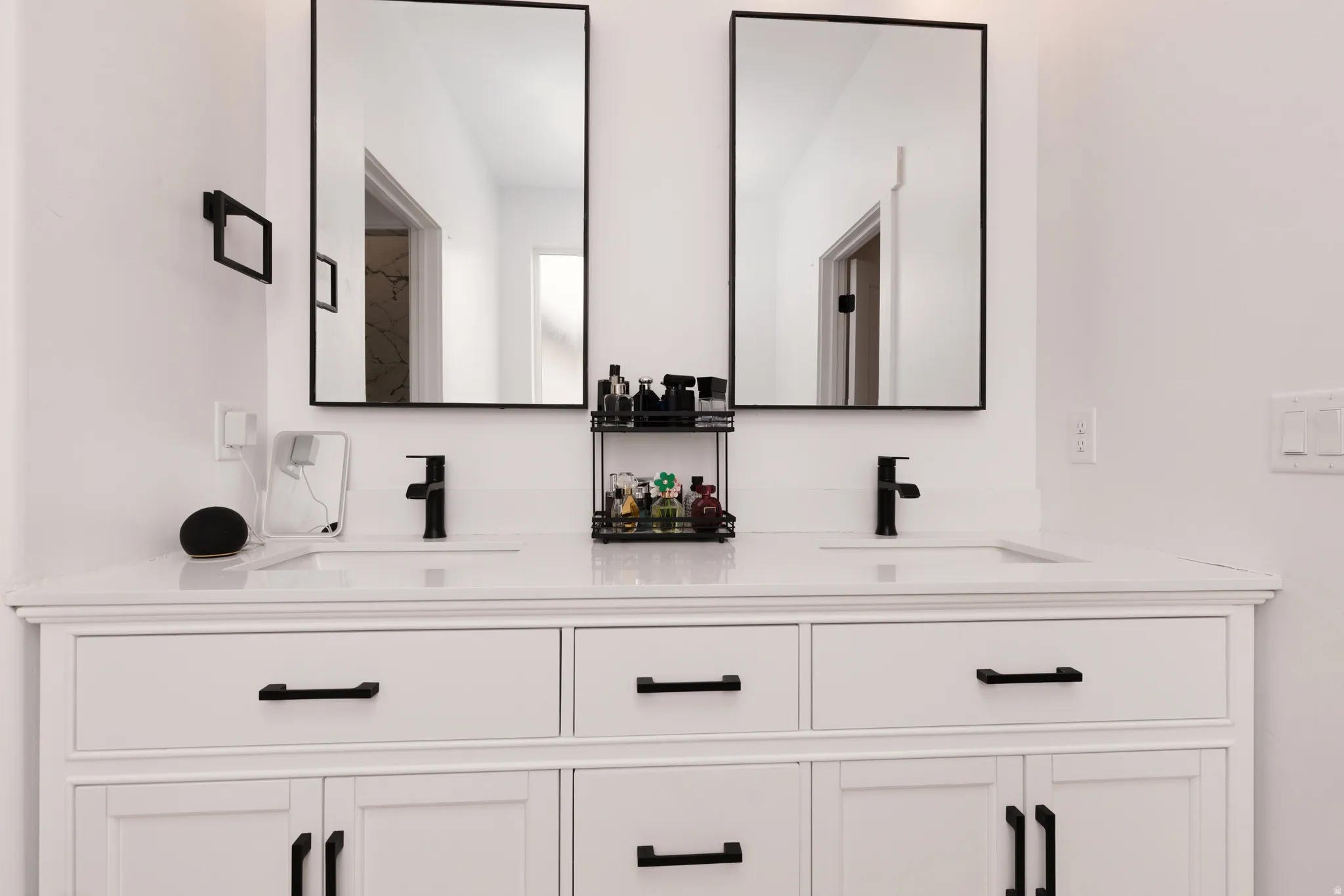 Double vanity with integrated sinks, white cabinetry, matte black hardware, and rectangular mirrors