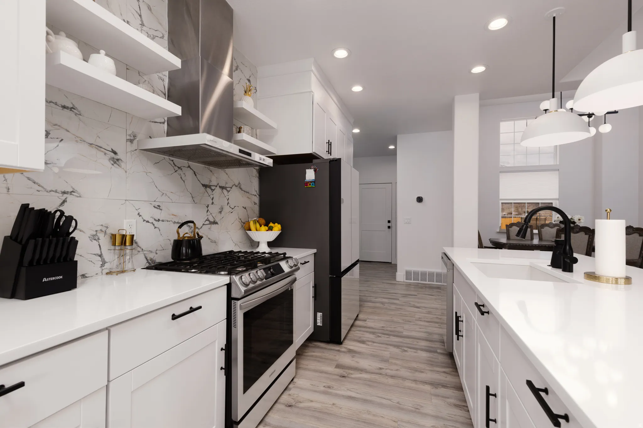 White cabinetry with matte black hardware, stainless steel appliances, marble-look tile backsplash, white countertops, and wood-finish flooring