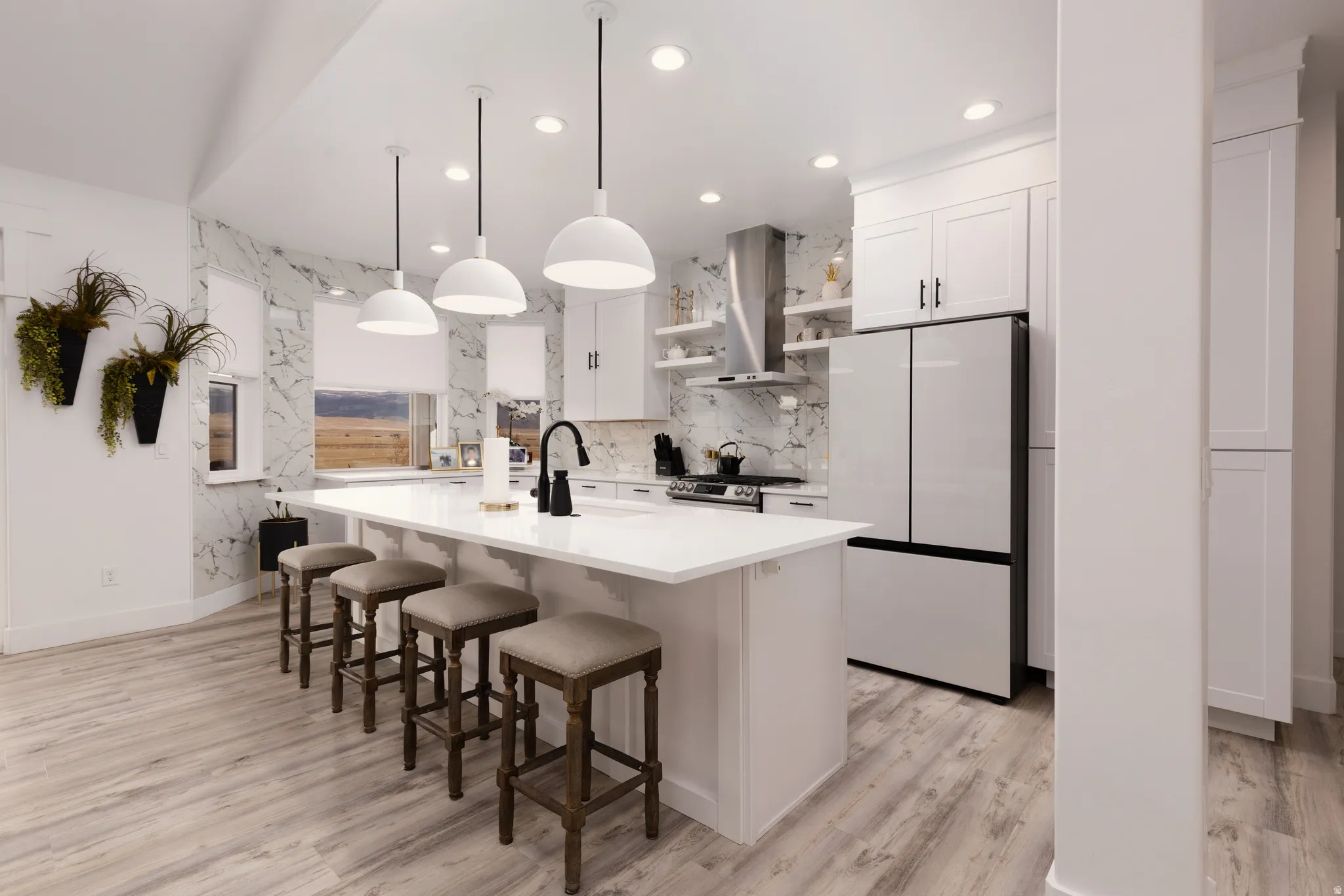 Open-concept kitchen with a large island, white shaker cabinetry, stainless steel appliances, and wood-finish flooring