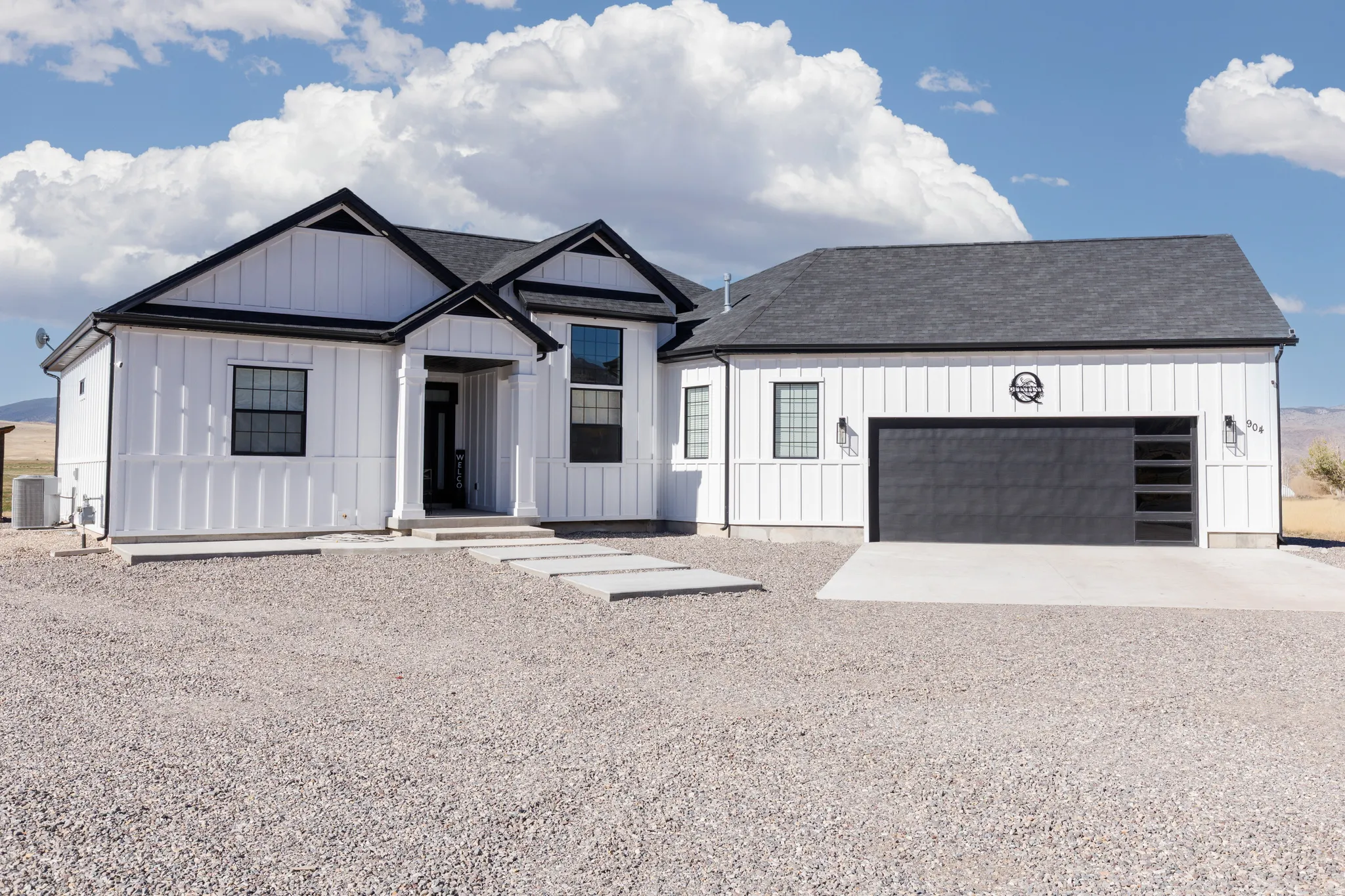 Board and batten exterior with contrasting black trim, covered entry, attached garage with modern glass-paneled door, and concrete walkway