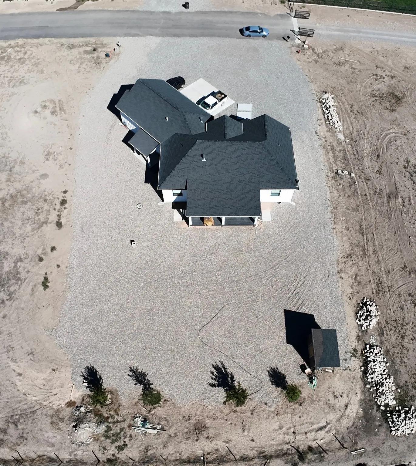 Expansive gravel-covered lot featuring a detached storage shed, partially fenced perimeter, and a paved driveway