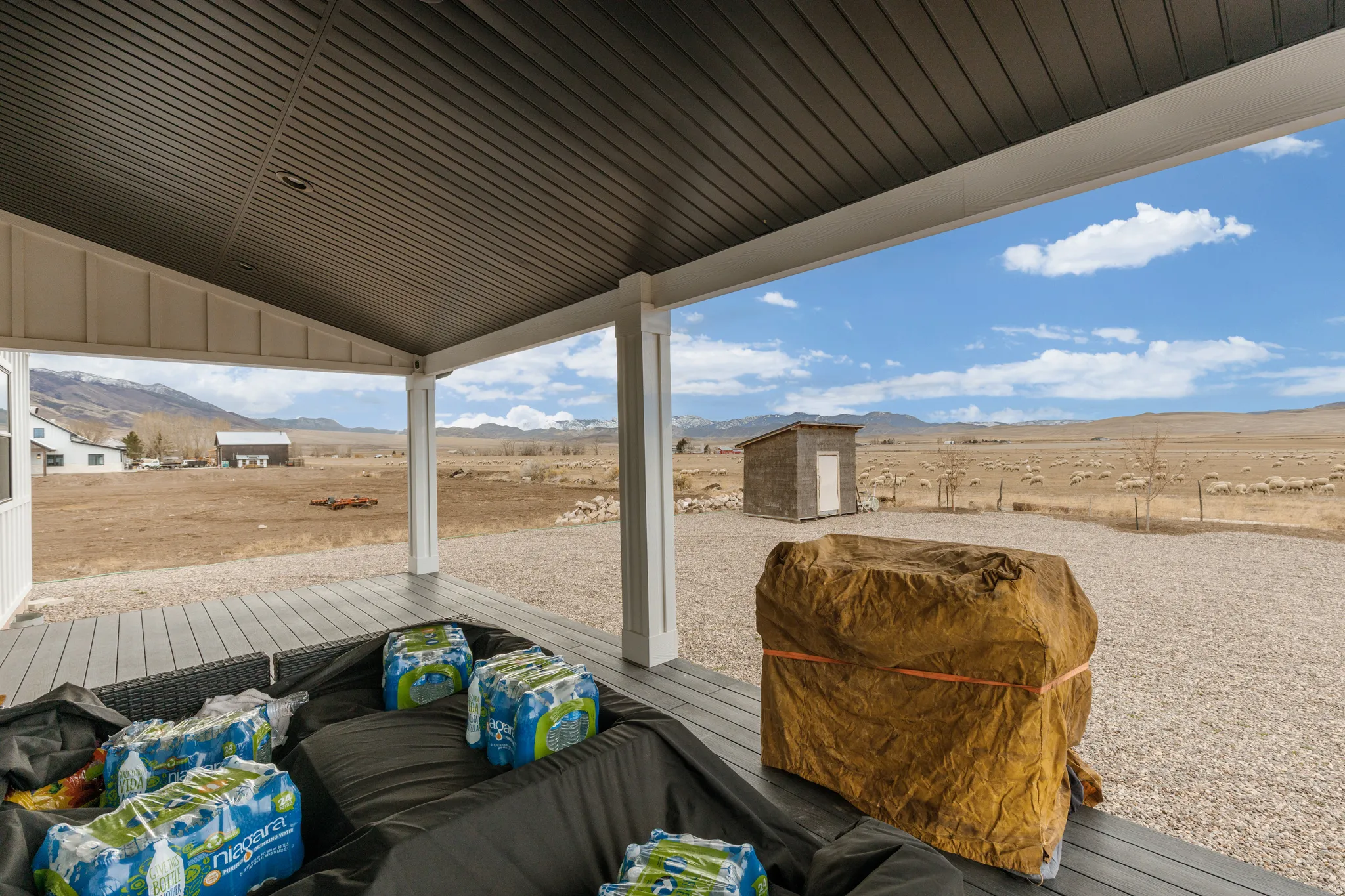 Spacious covered patio with light gray decking and white support columns