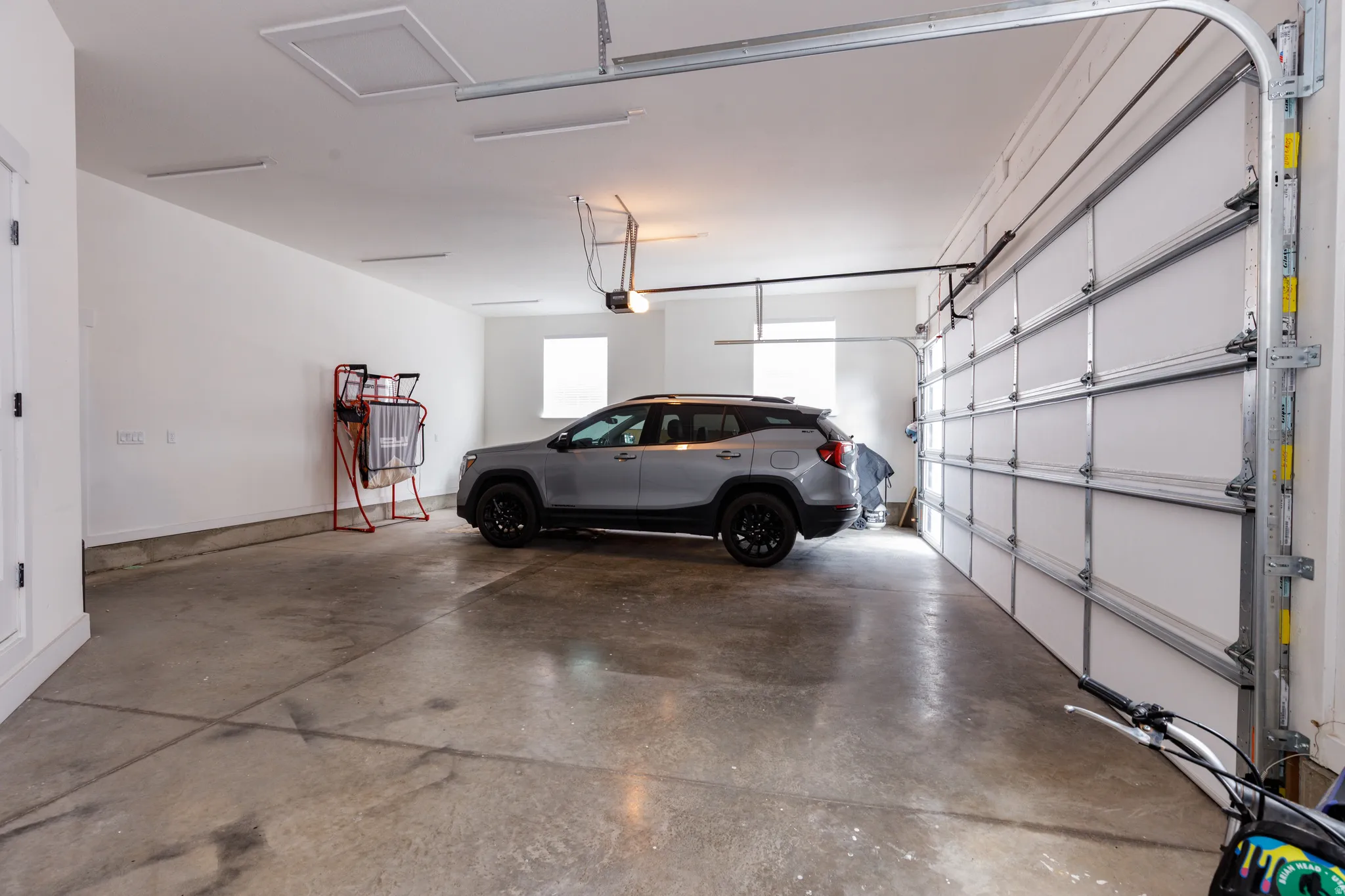 Attached garage with a concrete floor, white walls, and a sectional garage door