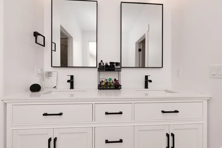 Double vanity with integrated sinks, white cabinetry, matte black hardware, and rectangular mirrors