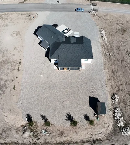 Expansive gravel-covered lot featuring a detached storage shed, partially fenced perimeter, and a paved driveway