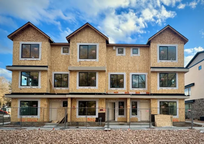 New construction multi-unit building featuring multiple gabled rooflines, dark-framed windows, and a partially complete exterior