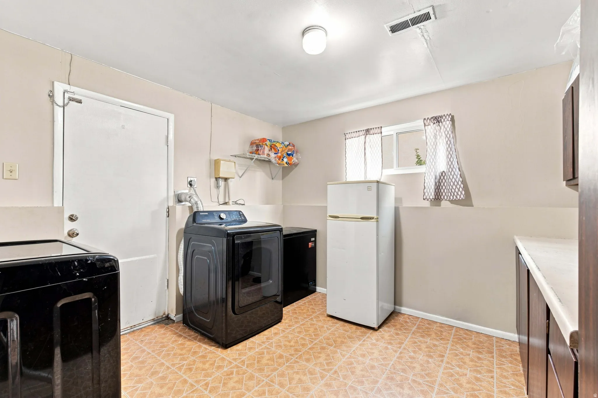 Laundry area with tiled flooring, a window, and built-in cabinetry