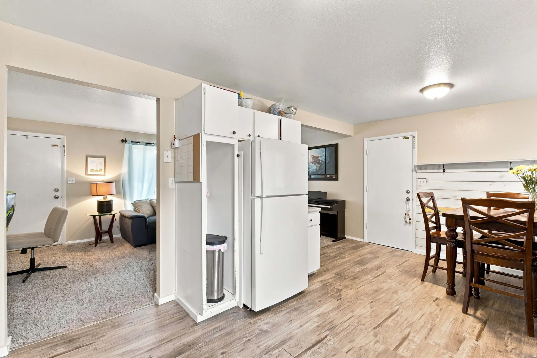 Kitchen area featuring wood-finish flooring, white cabinetry, and a white refrigerator