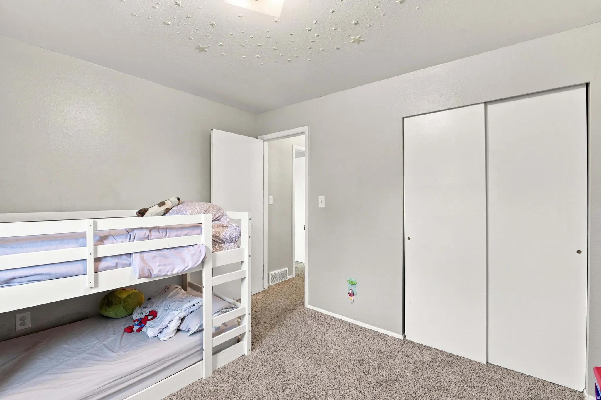 Carpeted flooring, light grey wall paint, and sliding closet doors