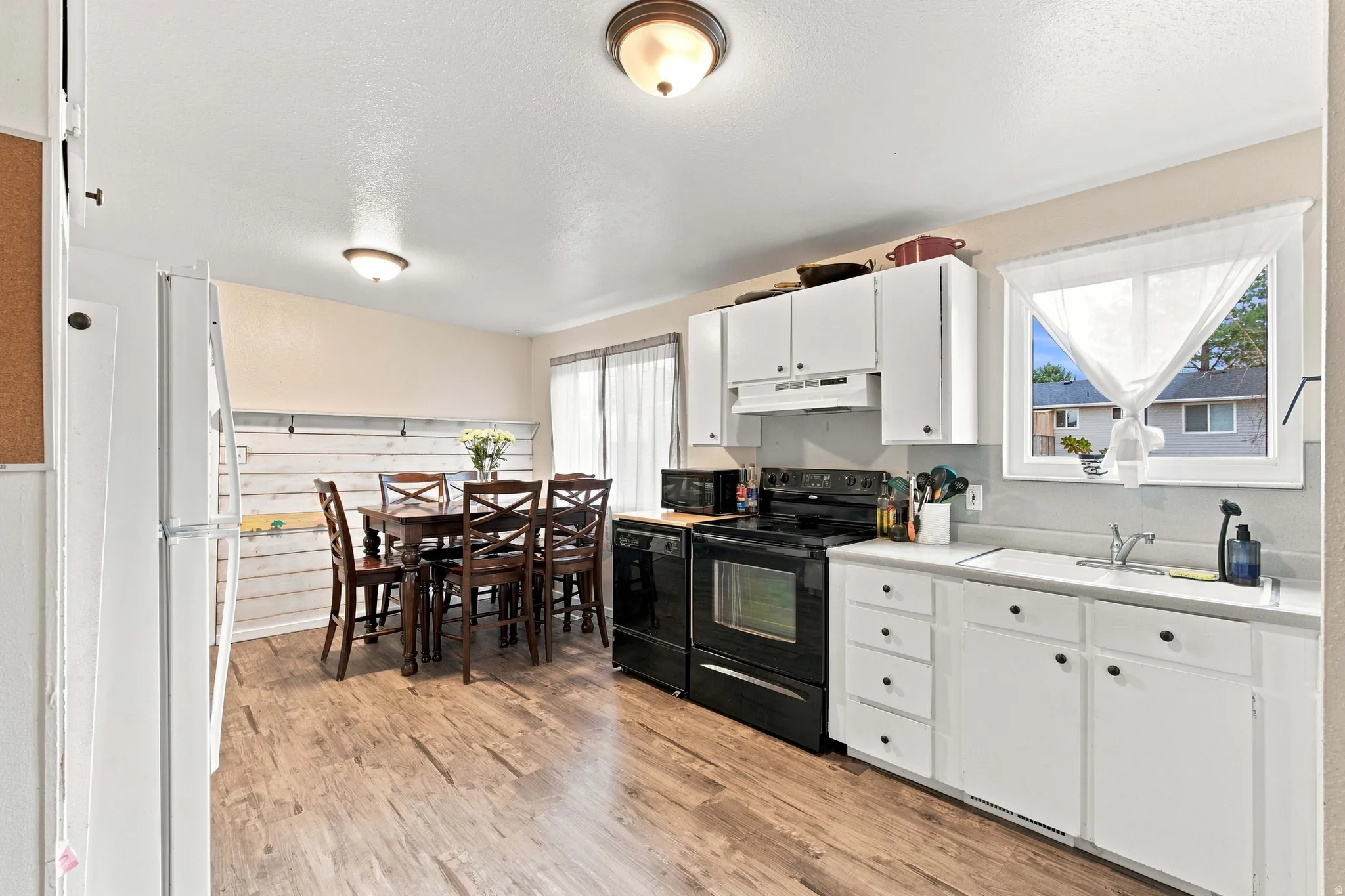 Kitchen featuring white cabinetry, black appliances, a double basin sink, and wood-finish flooring