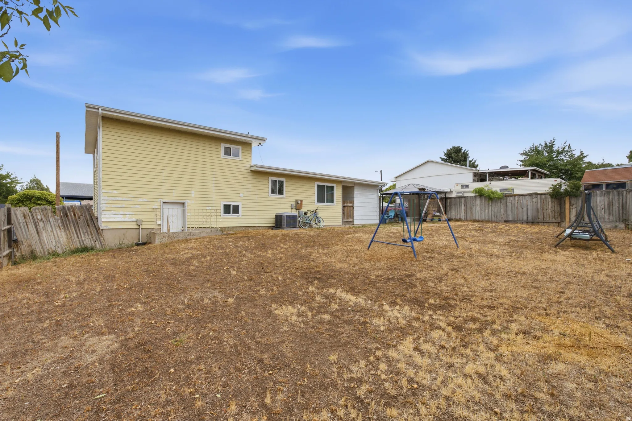 Expansive backyard area with a partial wood fence
