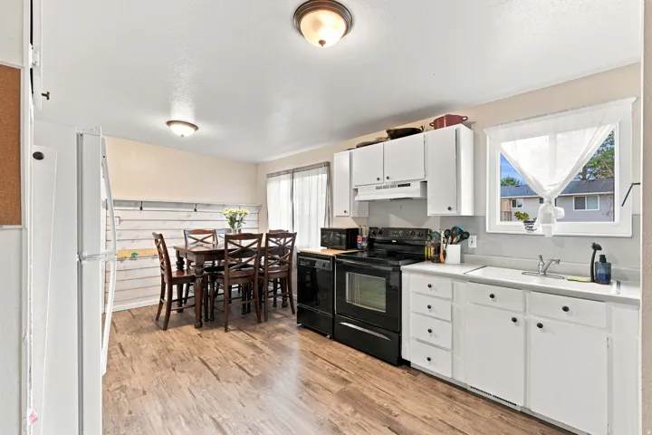 Kitchen featuring white cabinetry, black appliances, a double basin sink, and wood-finish flooring