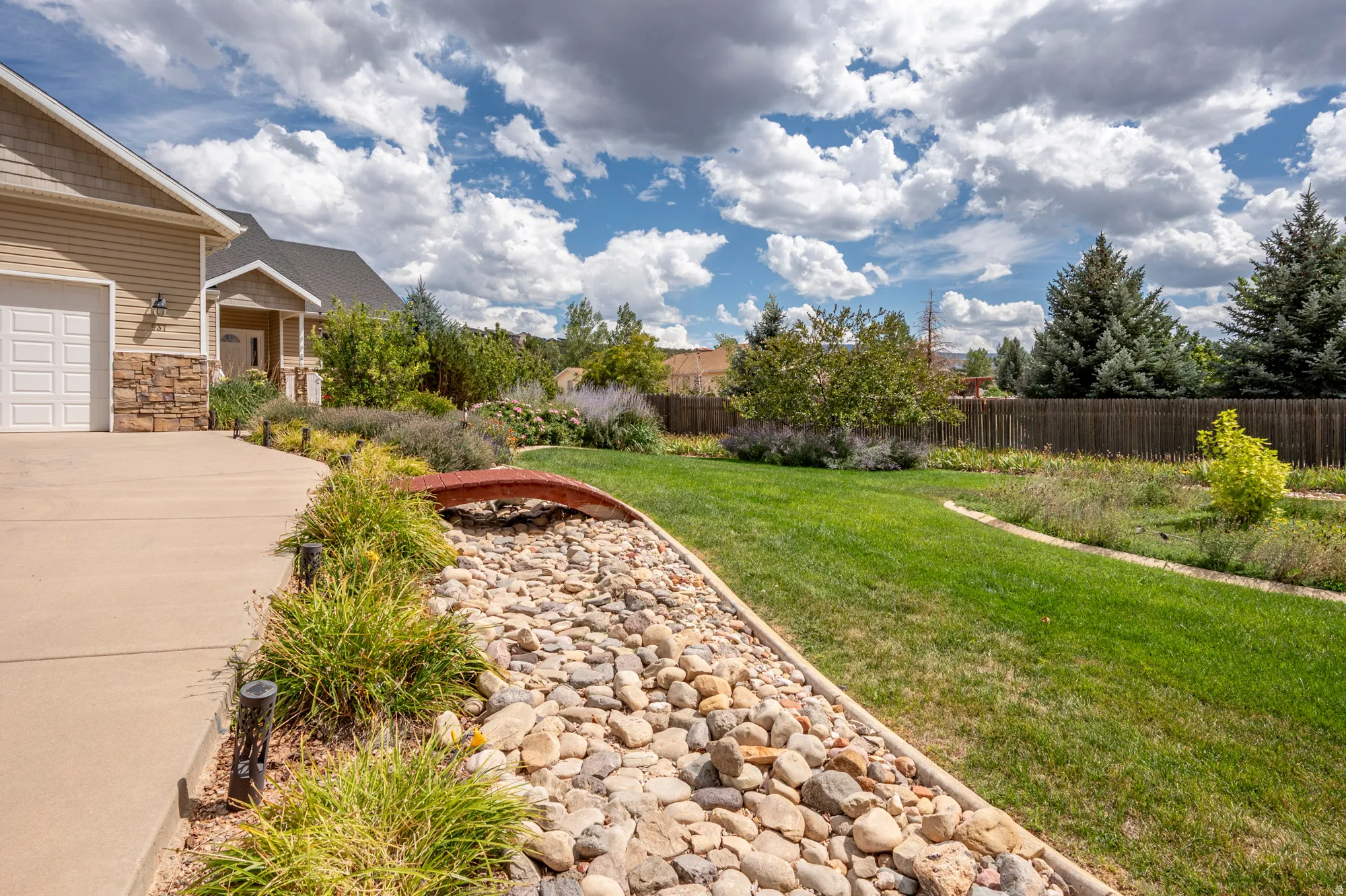 Expansive lawn with a decorative rock bed, mature trees, and landscaping