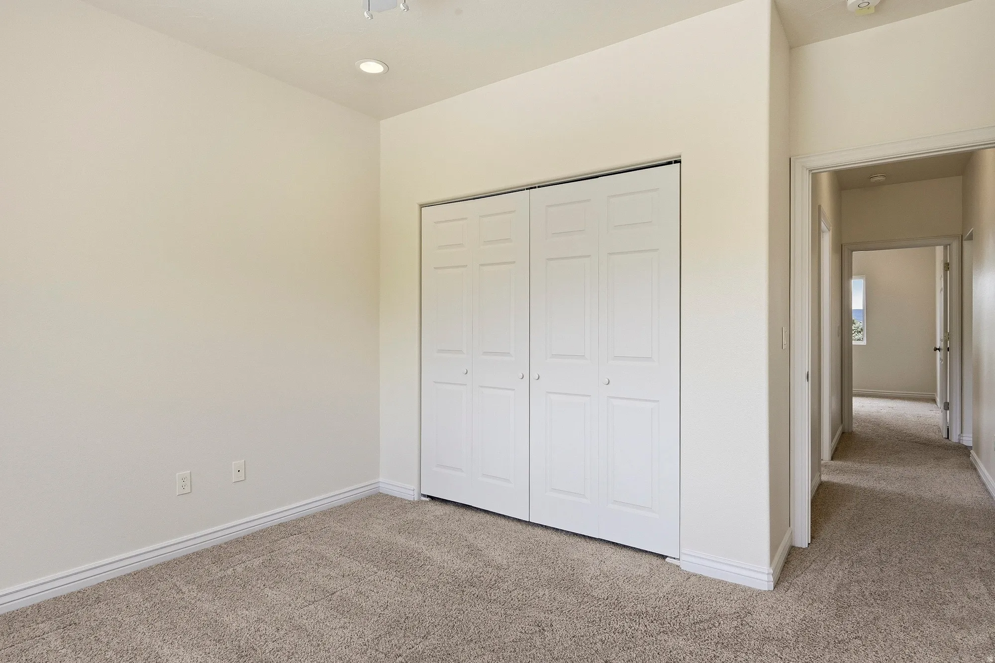 Recessed ceiling lighting, bi-fold closet doors, neutral wall color, and carpet flooring