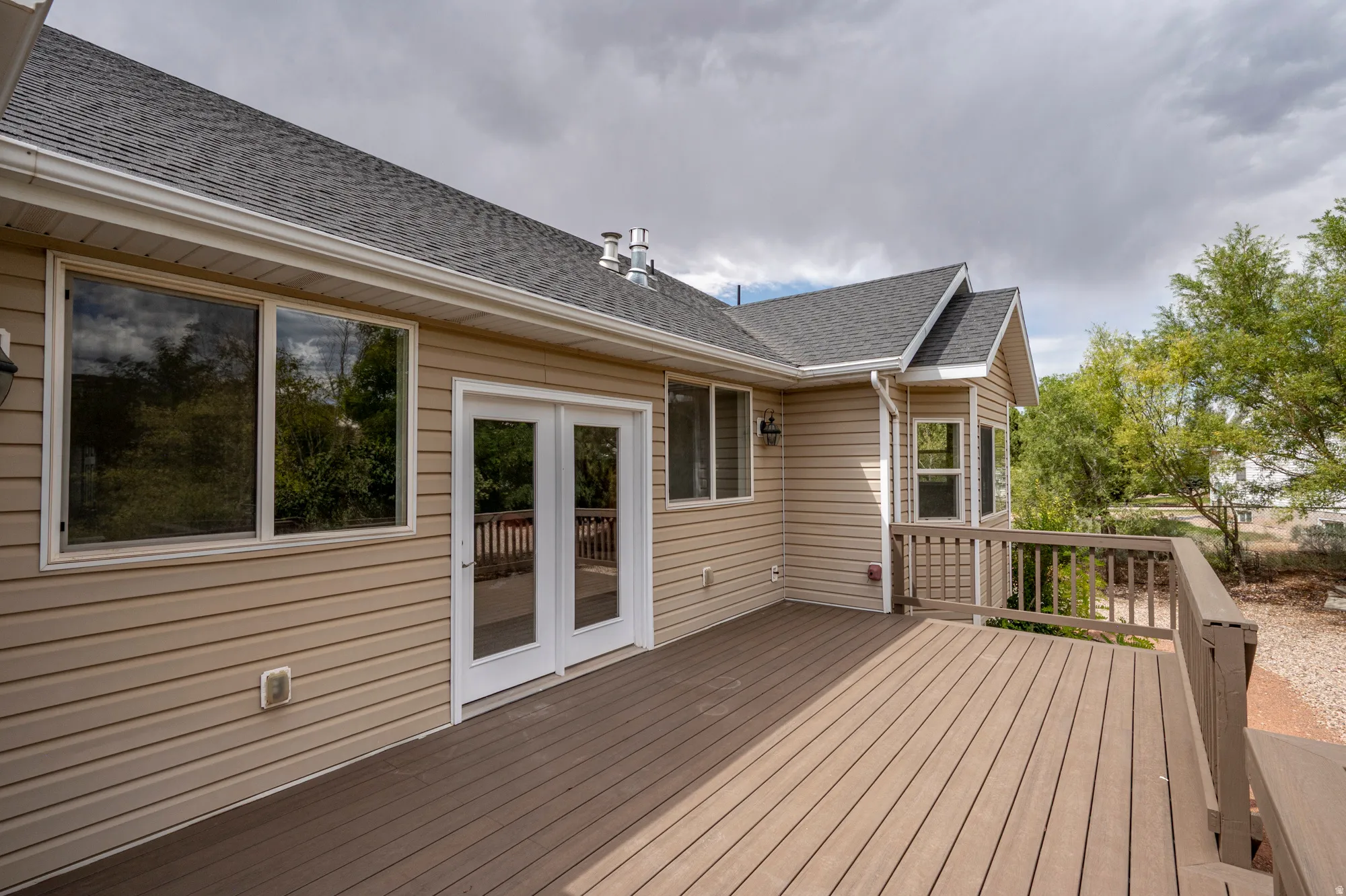 Expansive outdoor deck with composite decking, white double French doors, large windows, and a bay window extension