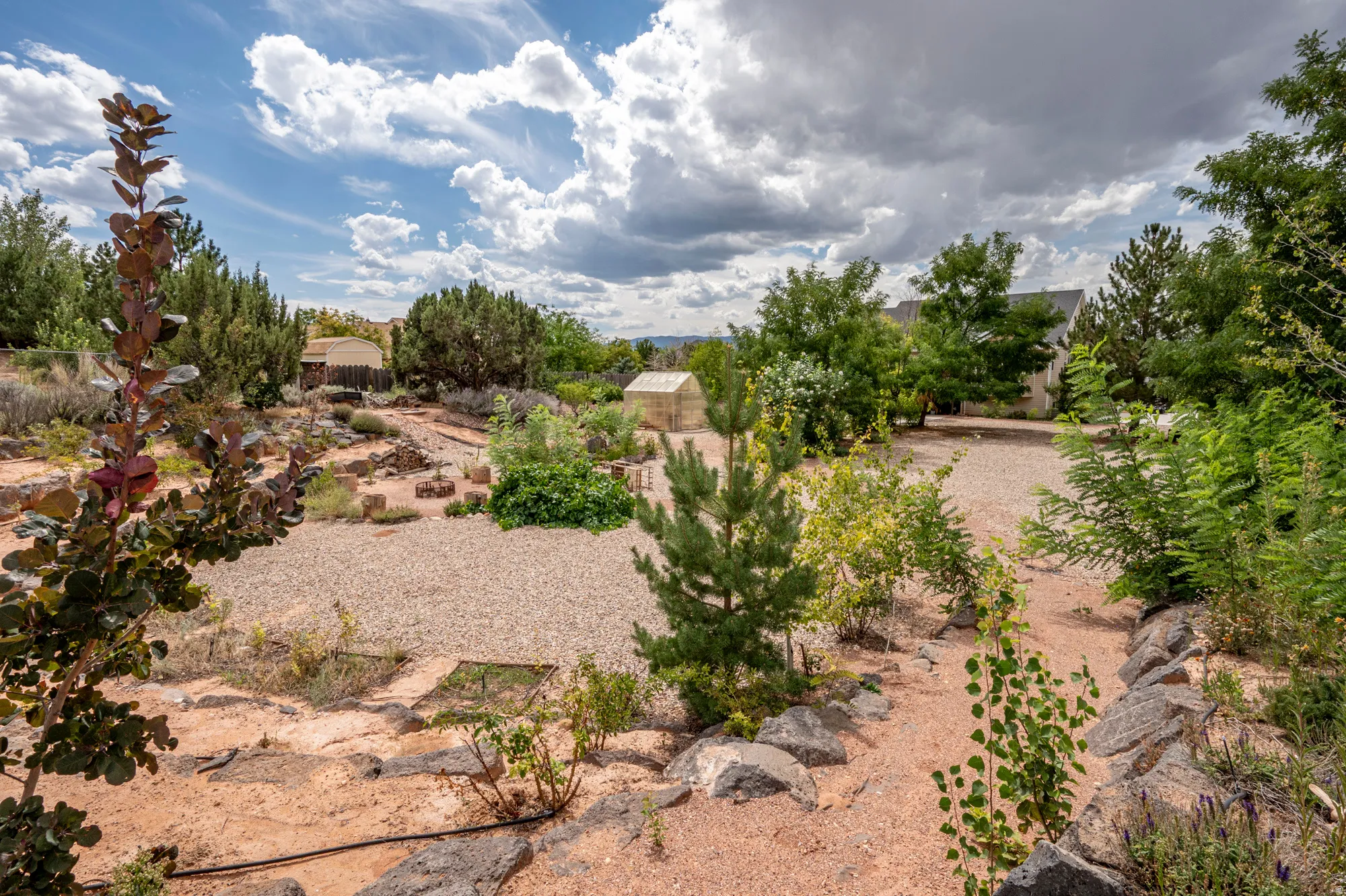 Landscaped grounds featuring a gravel path, diverse plantings, and rock formations