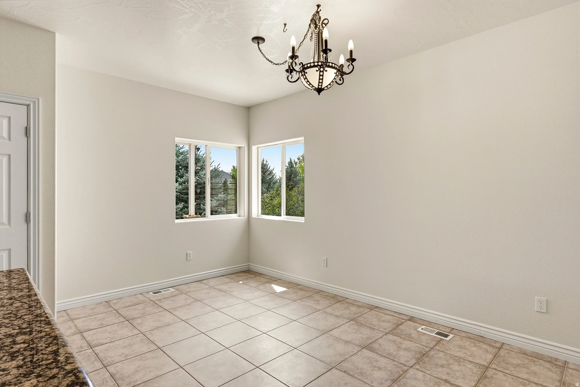 Ceramic tile flooring, corner windows, crown molding, and a chandelier