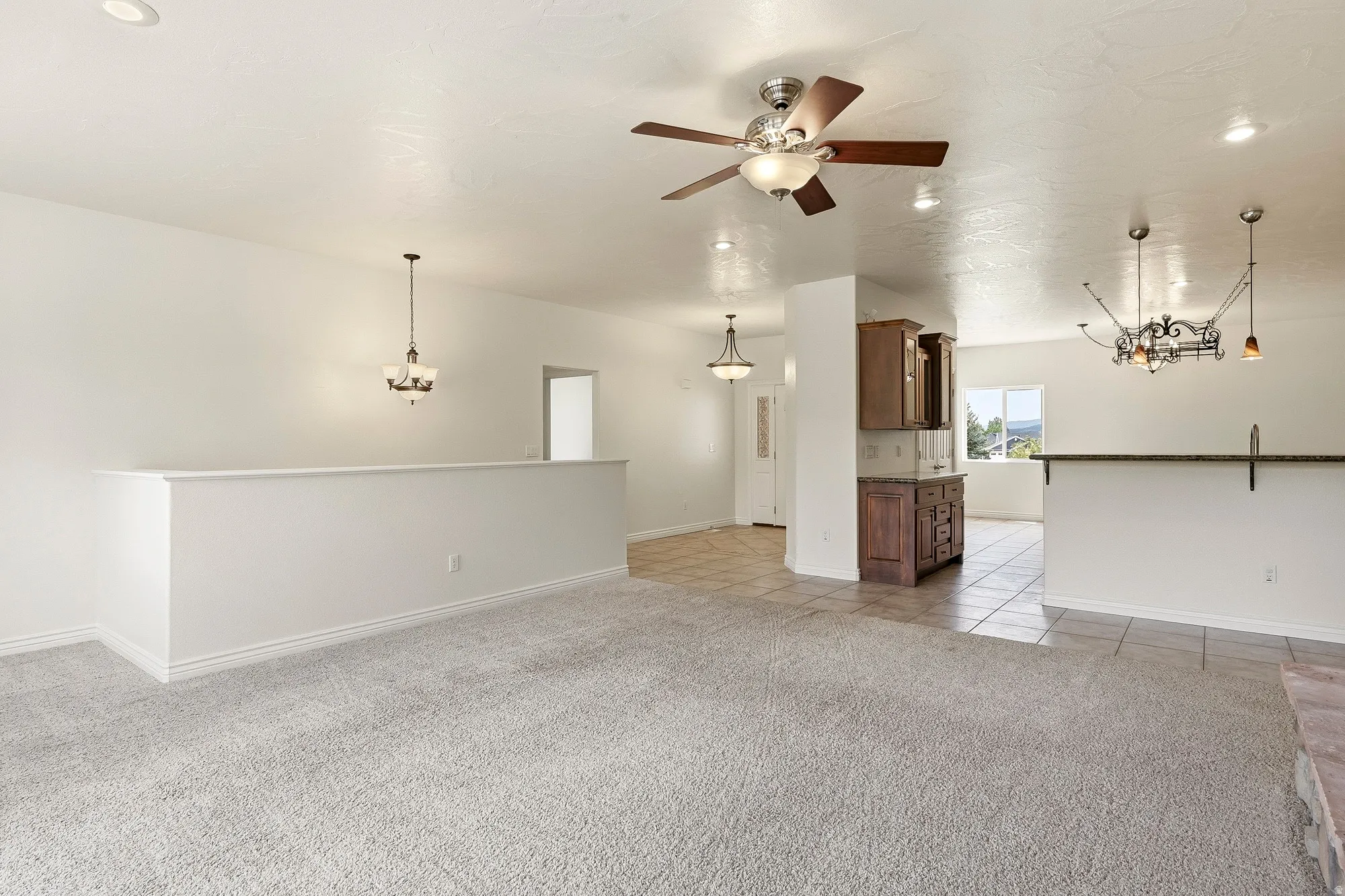 Neutral tone wall paint, recessed lighting, ceiling fan light fixture, tile flooring, and a built-in wood-finish cabinet
