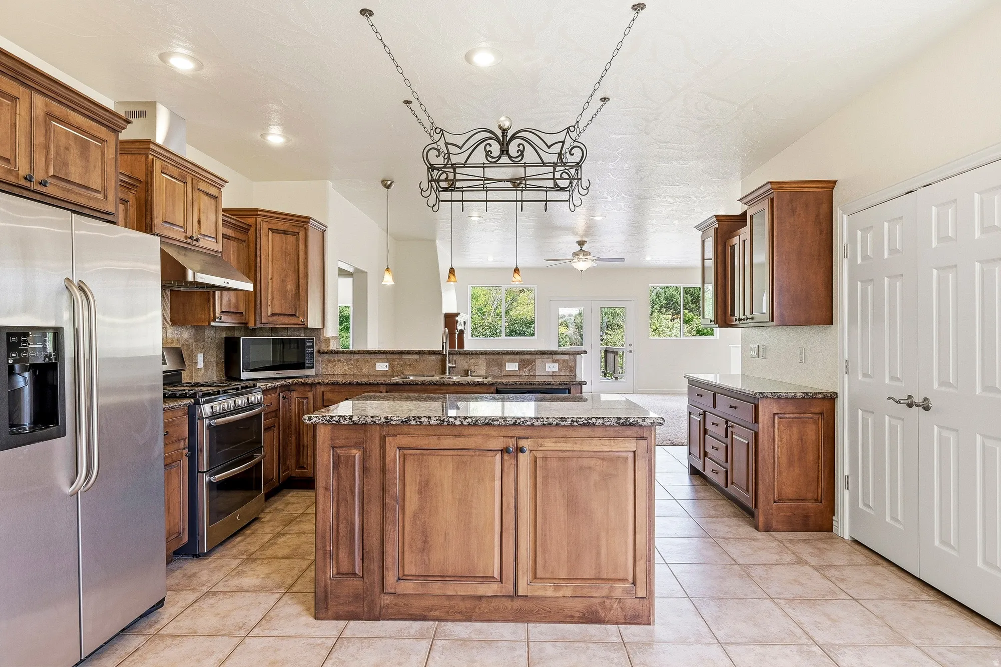 Kitchen with wood cabinetry, stainless steel appliances, a center island, and tile flooring