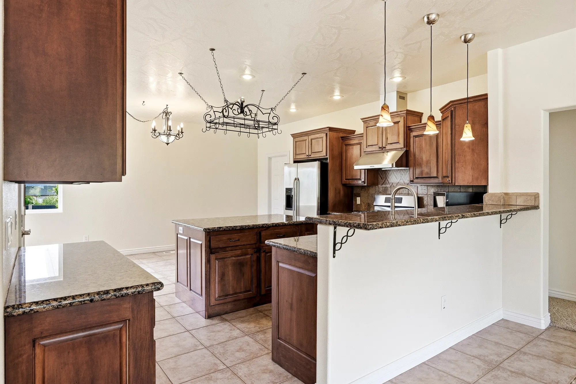 Kitchen featuring wood cabinetry, granite-style countertops, tile flooring, and stainless steel appliances