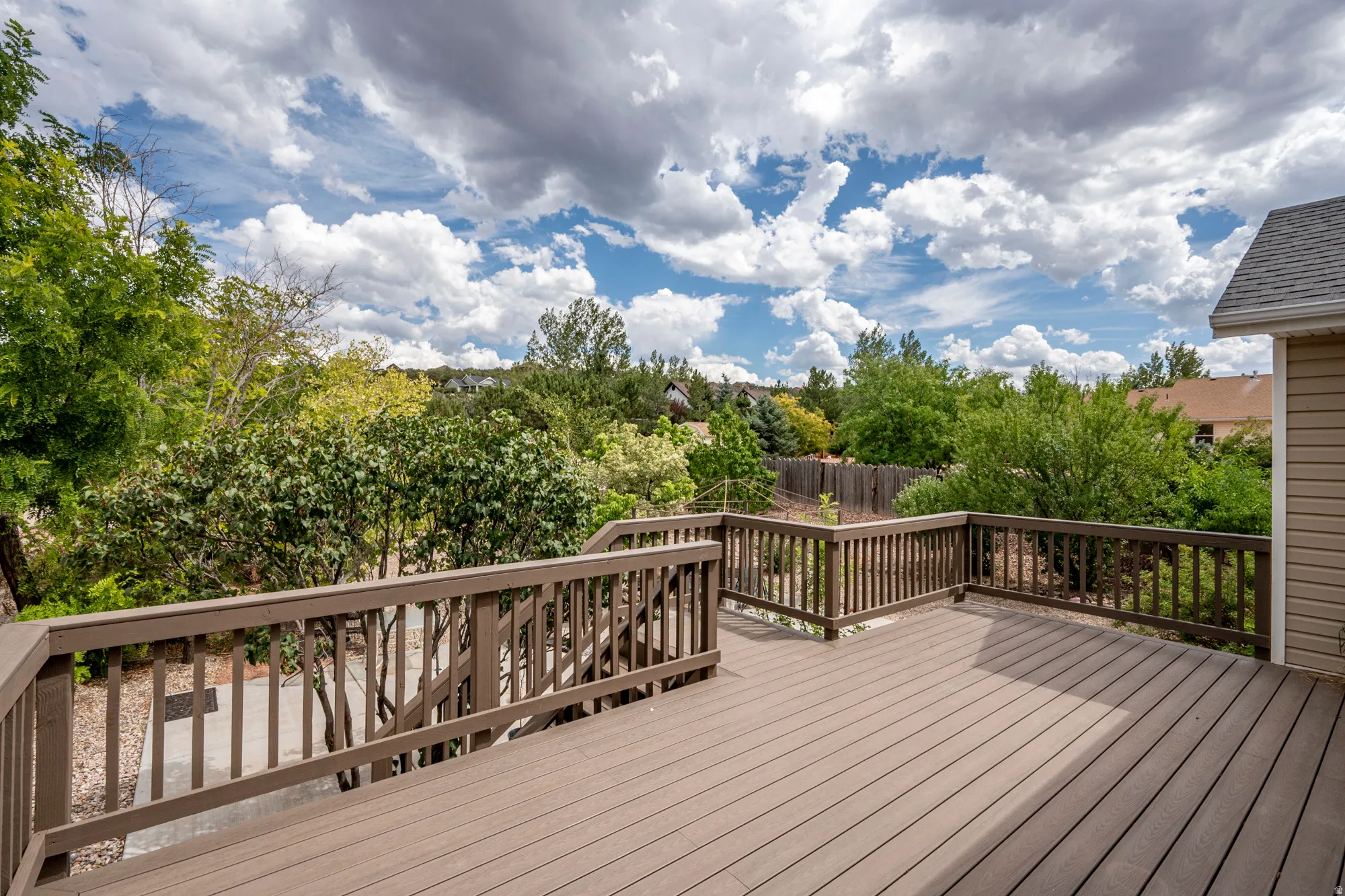 Expansive outdoor deck with wood-finish railing and siding, providing ample space for outdoor activities