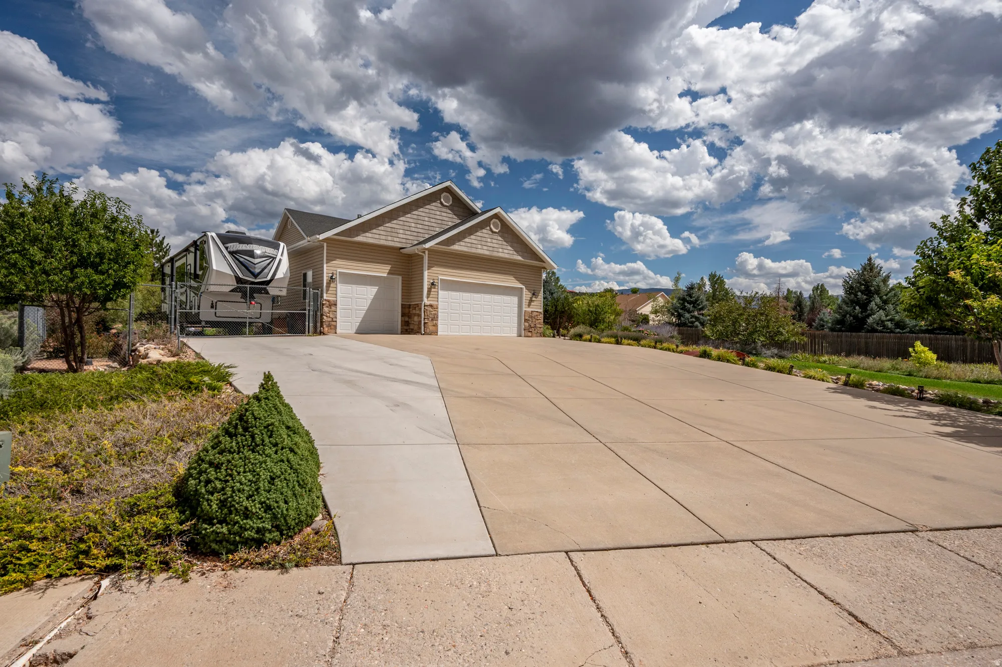 Exterior featuring a two-car garage, stone accents, and a wide concrete driveway
