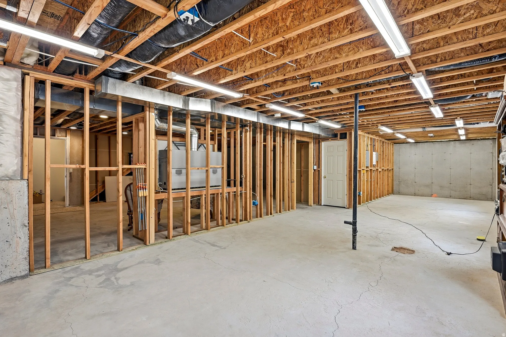 Unfinished basement featuring wood framing, concrete flooring, and exposed ceiling joists