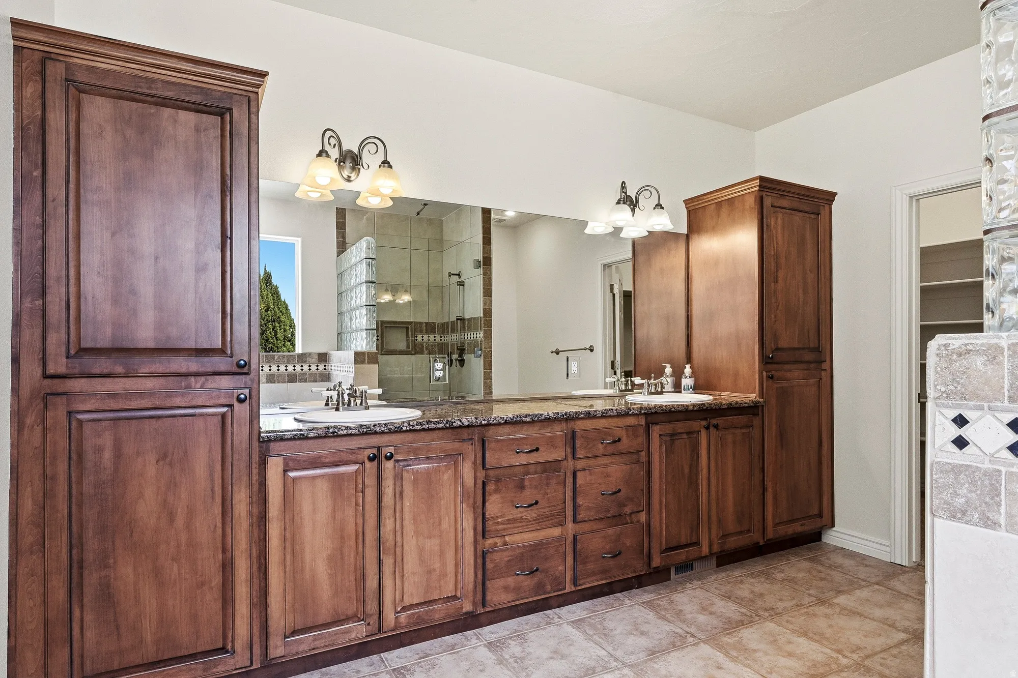 Dual vanity with wood cabinetry, integrated sinks, and polished countertops