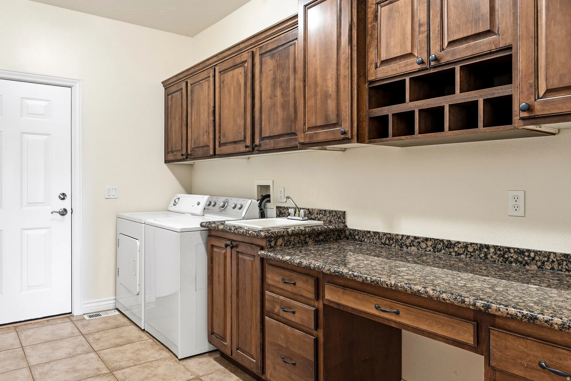 Built-in cabinetry with wood-finish doors, integrated sink, and stone-finish countertop
