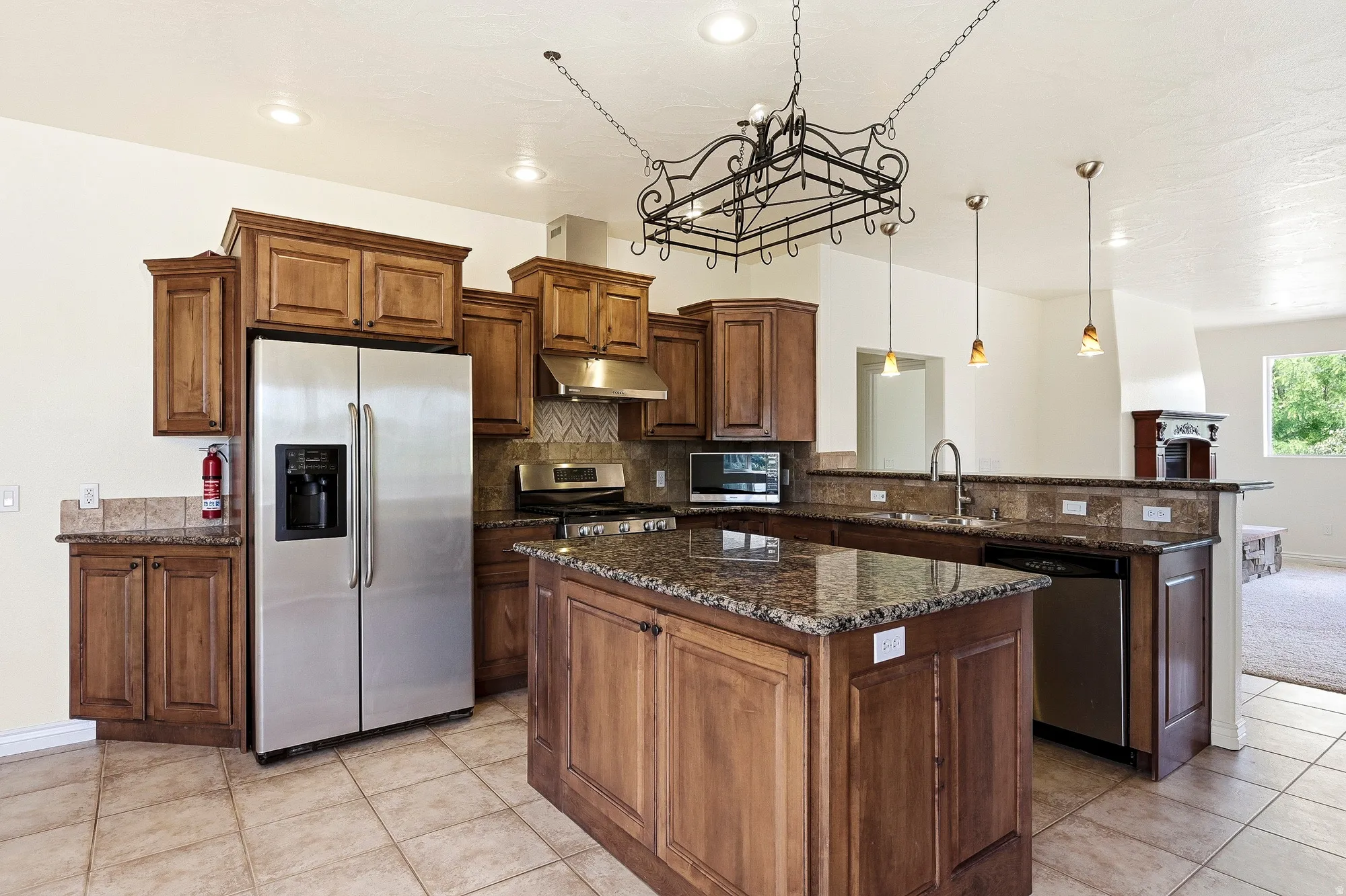 Kitchen featuring wood cabinetry, granite countertops, tile flooring, and stainless steel appliances