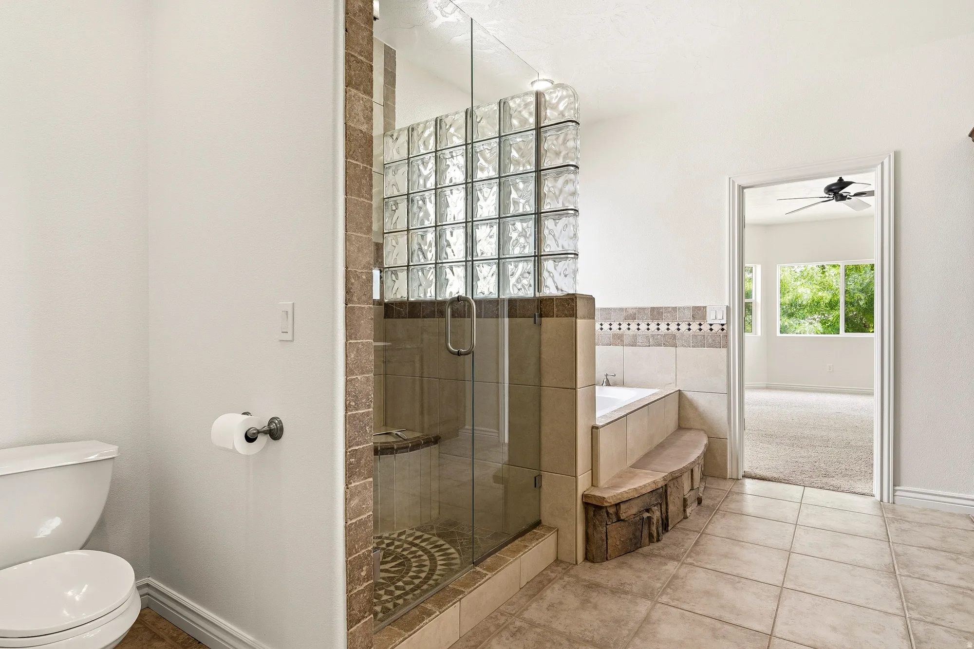 Tile flooring, glass block shower enclosure, full glass shower door, built-in bathtub, and a built-in bench