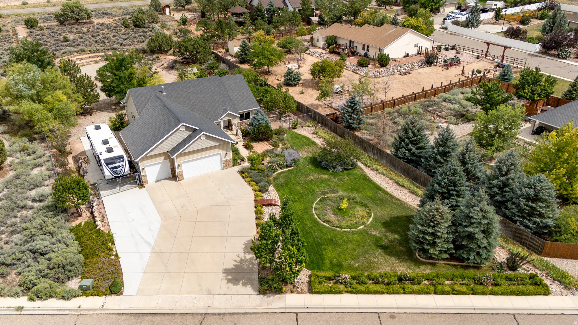 Elegant residence featuring a three-car garage, newly poured concrete driveway, and meticulously landscaped grounds with mature evergreen trees, native shrubs, and manicured lawn