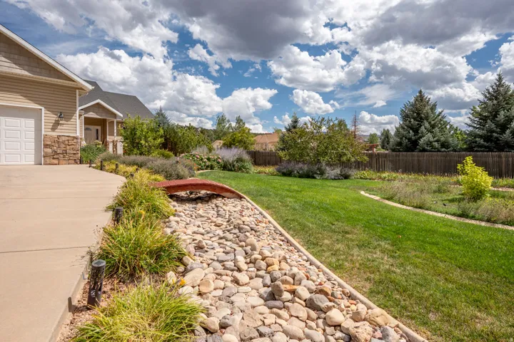 Expansive lawn with a decorative rock bed, mature trees, and landscaping